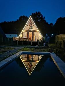 a house with a reflection in the water at night at Ashla A-Frame Lenkaran in Lankaran