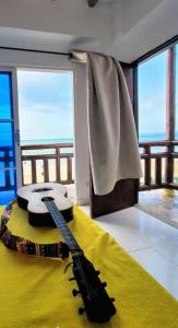a guitar sitting on a bed in a room with windows at Hotel Juanmar in Juan de Acosta
