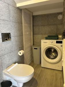 Un baño con lavadora y un inodoro. en Lāčplēšas ielas apartment 2, en Liepāja 6 fotos más