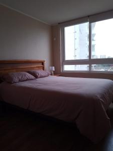 - une chambre avec un grand lit et une grande fenêtre dans l'établissement Departamento La Serena, à La Serena