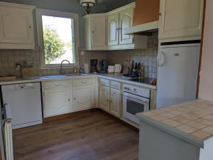 eine Küche mit weißen Geräten und einem Fenster in der Unterkunft L'orée du bois in Saint-Valery-sur-Somme + 23 Fotos