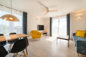 salon ze stołem i żółtym krzesłem w obiekcie APARTAMENTY ZATOKA w Jastarni