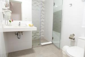 a white bathroom with a shower and a sink at Hotel San Blas in Lima