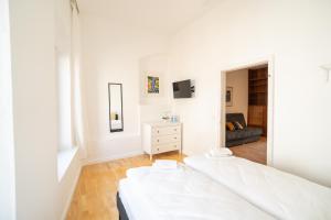 Stadtoase nähe Uni mit Sauna في كوبلنز: غرفة نوم بيضاء مع سرير وأريكة
