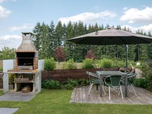 a patio with a table and an umbrella and a grill at Escapade en Ardenne - Appartement Sur Jardin Verdoyant in Bertrix