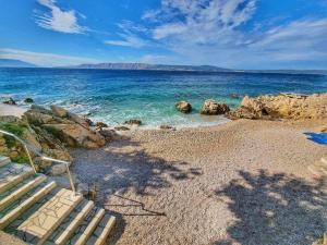 a bench sitting on a beach near the water at Ema Rooms in Novi Vinodolski