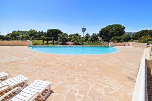 a swimming pool with white chairs and a stone patio at DUPLEX VILLA LES PINS 89m2 et terrasse 30m2 in Antibes