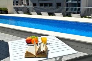 a table with fruit and drinks next to a pool at Hostal Rambla 24 by Holihome in Alicante