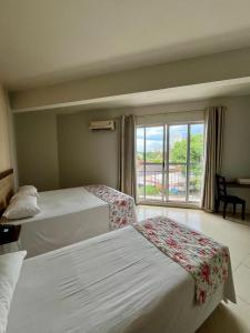 um quarto de hotel com duas camas e uma janela em Moura Palace Hotel em Foz do Iguaçu