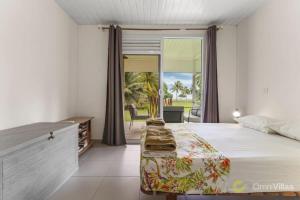 モーレア島にあるSeaside Paradise Retreat - 3BR House in Mooreaのベッドとガラスの引き戸のある寝室
