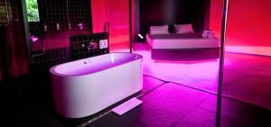 a bath tub in a room with pink lighting at Andar de Cima Suítes in Sao Paulo