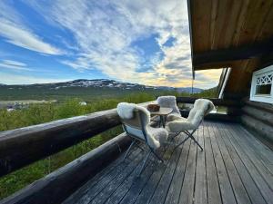 two chairs and a table on the deck of a cabin at Unique Arctic Timber Cabin in Skaidi