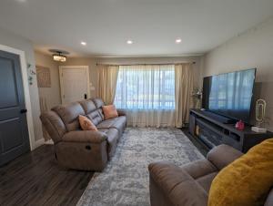 a living room with couches and a flat screen tv at Harmony Haven in Lower Sackville