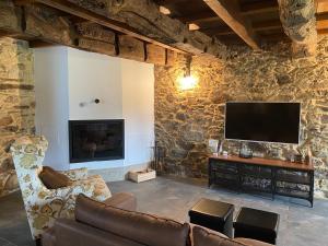 a living room with a stone wall with a flat screen tv at CASA PEINADO in Boimorto