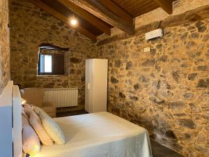 a room with a bed and a stone wall at CASA PEINADO in Boimorto