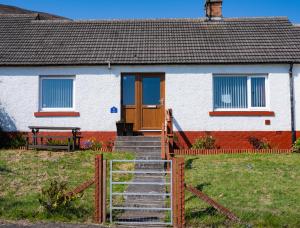 ein Haus mit einer Holztür und einer Treppe davor in der Unterkunft Luxury North Coast 500 Cottage by Helmsdale, stunning sea views in Portgower