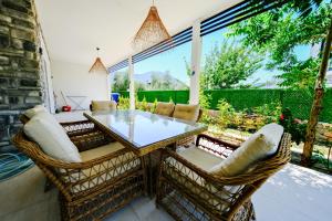 un patio avec une table en verre et des chaises en osier dans l'établissement Green Hills Luxury Villa Fethiye, Yesiluzumlu by Sunworld Villas, à Fethiye