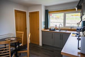 eine Küche mit Tisch und Spüle und Fenster in der Unterkunft Luxury North Coast 500 Cottage by Helmsdale, stunning sea views in Portgower