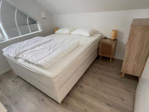 1 cama blanca en un dormitorio con ventana en Strandferie på Sørlandet en Kristiansand