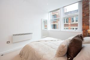 a white bedroom with a bed and a window at Boutique City Centre Apartment in Manchester