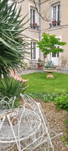 a white bench in a garden with a building at agréables chambres d'hôtes près du centre ville avec jardin in Le Mans