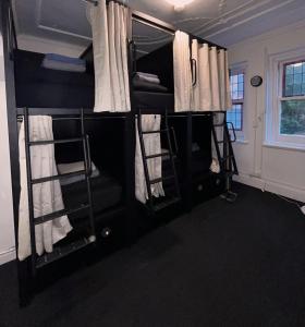 シドニーにあるPotts Point Hostelの白いカーテン付きの二段ベッド2台が備わる客室です。