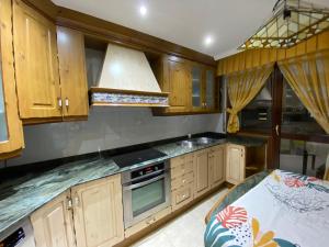 cocina con armarios de madera y horno con fogones en Apartamento El Rincón de Pilar en El Astillero