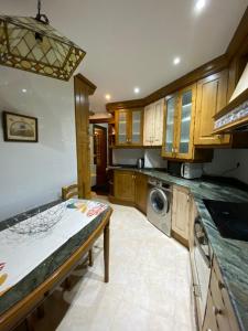 a kitchen with wooden cabinets and a washer and dryer at Apartamento El Rincón de Pilar in El Astillero +11 photos