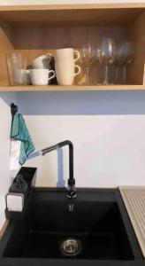 a kitchen counter with a sink and some cups and glasses at Apartment by seaside in Ķesterciems
