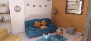 a blue couch in a living room with a clock at Agréable Maison plein centre in Fourques