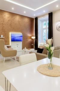 uma sala de estar com uma mesa branca com um vaso de flores em Apartman Mirakul em Subotica