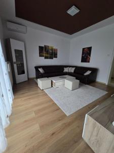 a living room with a black couch and two white tables at Apartman Nia in Bihać +18 photos