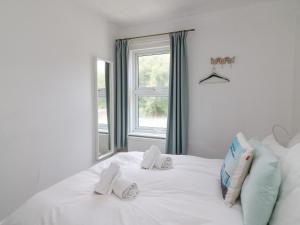 ein Schlafzimmer mit einem weißen Bett mit einem Fenster in der Unterkunft Gone Fishing in Weymouth