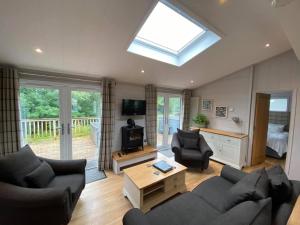 a living room with a couch and chairs and a television at Creel Lodge in Eyemouth