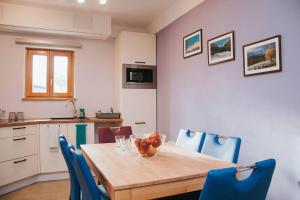 a kitchen with a wooden table and blue chairs at Apartment Kapitan with climbing wall in Kobarid