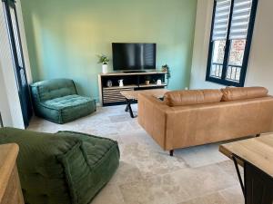 a living room with a couch and a flat screen tv at Gîte La Villa Marcelle in Mareuil-le-Port