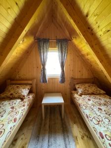 two beds in a log cabin with a window at Mountain Houses Šarović in Žabljak