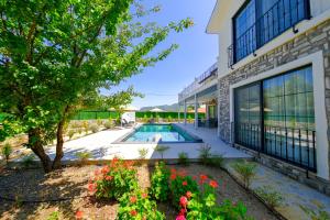 une vue extérieure d'un bâtiment avec piscine et fleurs dans l'établissement Misty Mountain Luxury Villa Fethiye, Yesiluzumlu by Sunworld Villas, à Fethiye