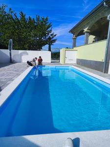 Dos personas arrodilladas junto a una piscina azul en Apartments Flora, en Medulin