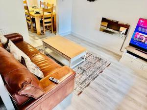 a living room with a brown leather couch and a table at Luxury 4 bed house in Coventry in Coventry