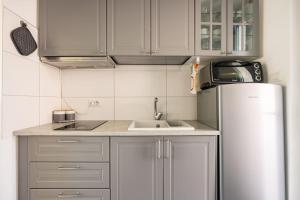 une cuisine avec des armoires blanches et un réfrigérateur en acier inoxydable dans l'établissement Cosy apartment near the Lake, à Riva del Garda