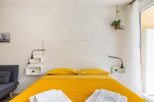 - une chambre avec un lit jaune et un canapé dans l'établissement Cosy apartment near the Lake, à Riva del Garda