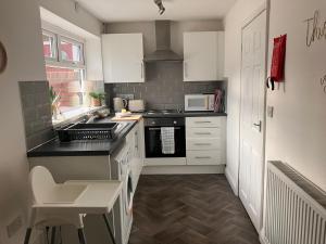una cucina con armadi bianchi e piano cottura di Sunderland Stays - Smart House Close to City Center Nissan and CrownWorks Studios a Sunderland
