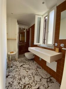 une salle de bain avec un lavabo, des toilettes et un miroir dans l'établissement Cefalhub, à Cefalù 37 autres photos
