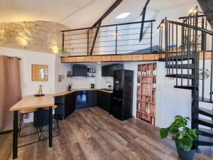 a kitchen with a spiral staircase and a loft at Duplex Le Chai de l'Abreuvoir in Saintes
