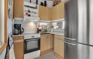 uma cozinha com um frigorífico de aço inoxidável e armários de madeira em Cozy Home In Assens With House Sea View em Assens