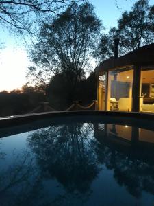 a house with a reflection in a swimming pool at Craigmaddie Muir Roundhouse with Hot Tub Romantic, Luxury, Rural Stay for 2 Near Milngavie in Glasgow