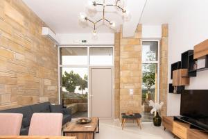 a living room with a stone wall and a chandelier at Rikanthos Stone Sea View Apartment ΙΙ in Kissamos