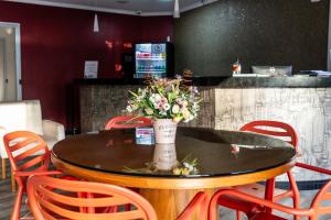 une table avec un vase et des fleurs sur lui dans l'établissement Hotel San Telmo, à Aparecida 16 autres photos