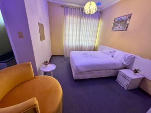 ムババーネにあるGoldenWays Motelのベッドと椅子付きの小さな部屋です。